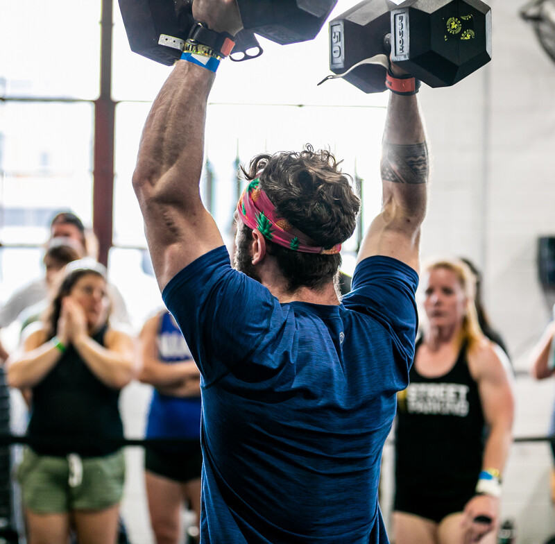 Crossfit athlete performing a shoulder press with dumbbells